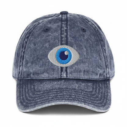 Navy washed denim dad hat with embroidered evil eye, centered on a pure white background with uniform padding